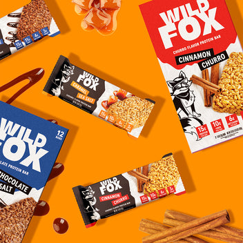 Wild Fox protein bars on an orange background with additional cinnamon sticks.